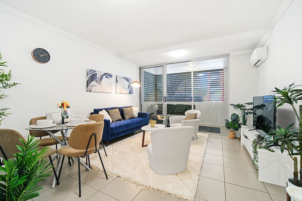 Living room with a navy sofa, dining table and pot plants