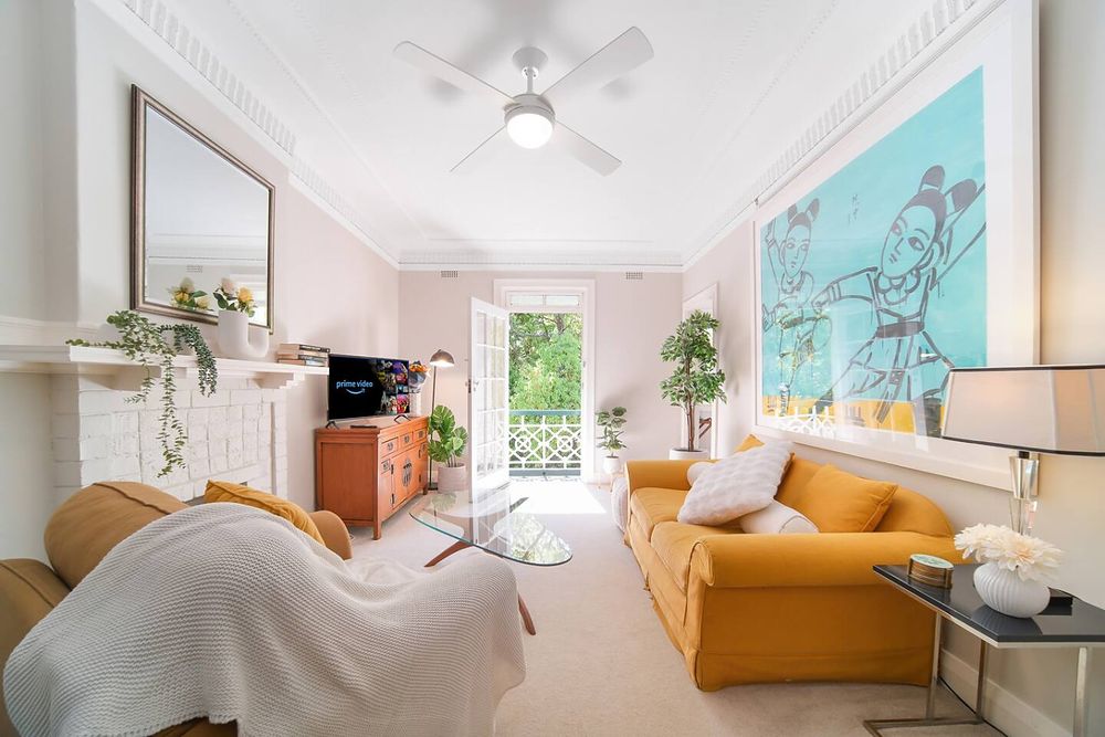 Living room with mustard sofas, a ceiling fan and French doors