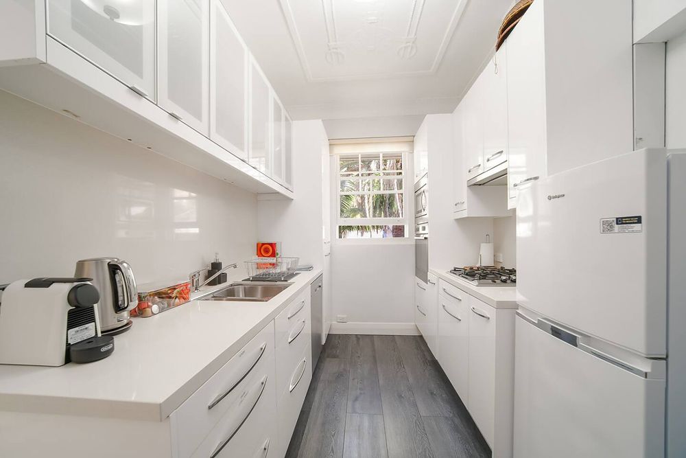White galley kitchen with a window at the end