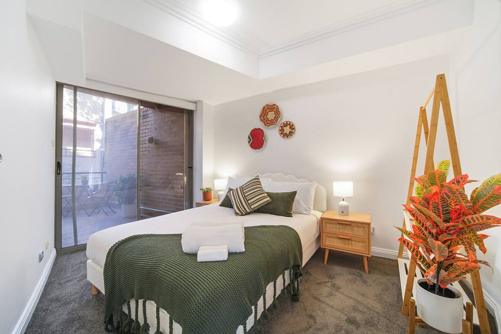 Bedroom with a green throw and a door to the balcony