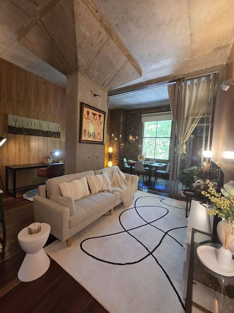 Living room with a pale sofa, timber-lined walls and a high ceiling