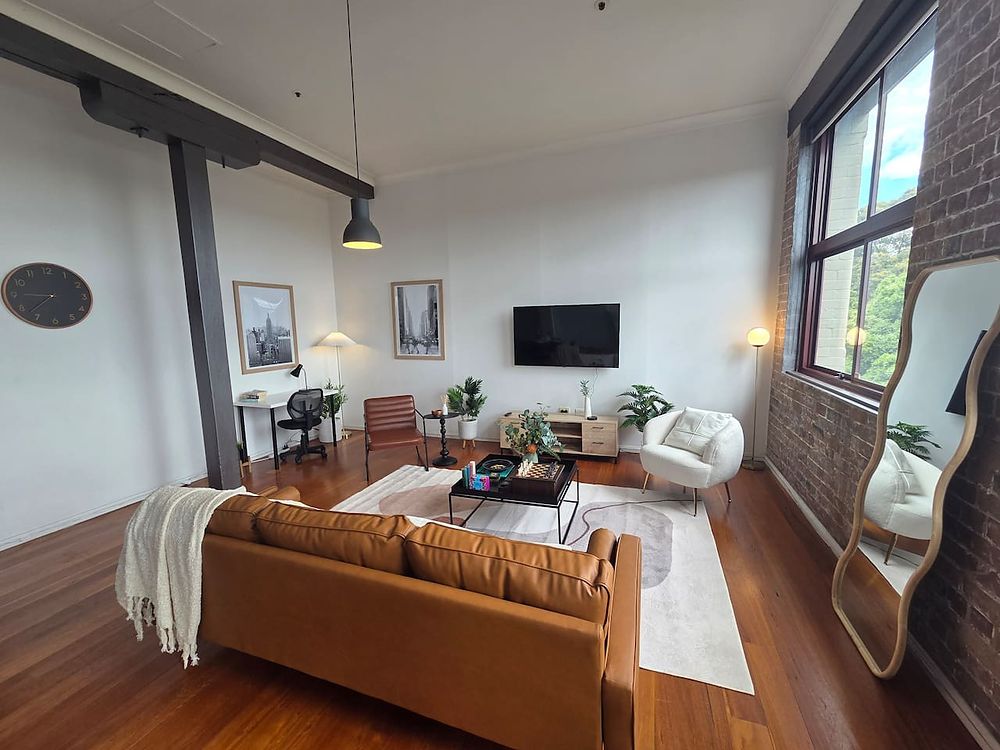 Living room with a leather sofa, tall windows and a brick wall