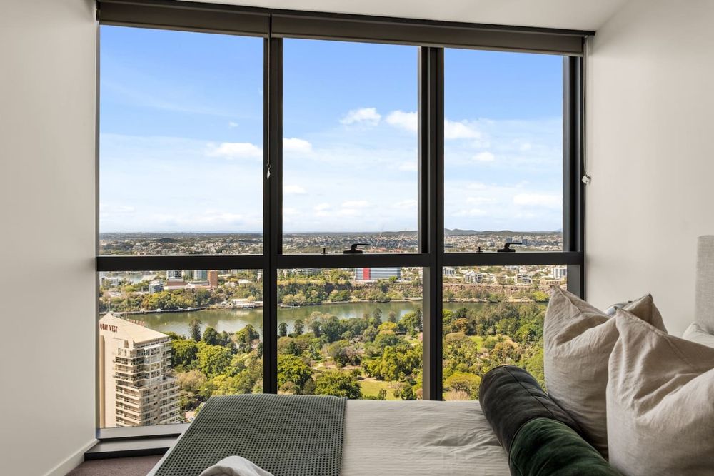Bedroom with floor-to-ceiling windows over the river and parkland